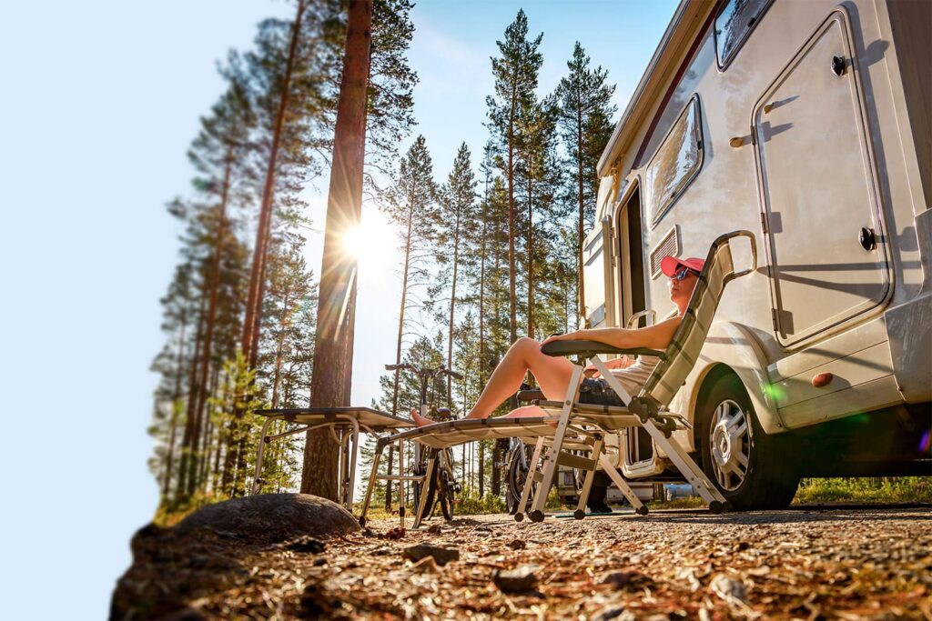 Relaxing man on infinity chair outside his RV in a remote forest.