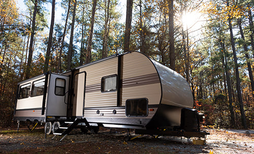 RV in the forest as the sun shines on it