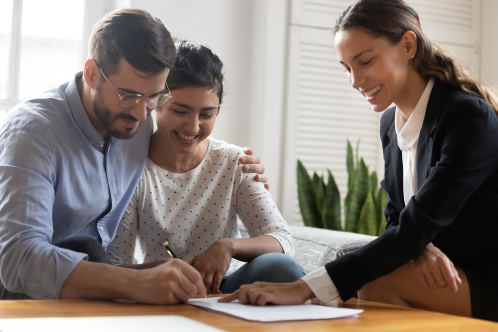man and woman looking to apply for a loan as broker looks on